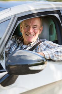 Portrait Of Smiling Senior Man Driving Car